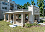 Thumbnail 11 of 20 - A small white building with a porch is in front of a multi-story apartment building.
