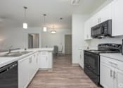 Thumbnail 13 of 20 - A kitchen with white cabinets and black appliances.