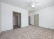 Thumbnail 10 of 20 - A room with a ceiling fan and carpeted floor.