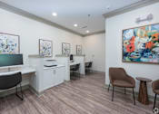Thumbnail 16 of 20 - A room with a desk, chairs, and a painting on the wall.
