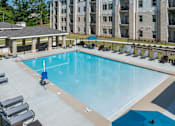 Thumbnail 6 of 20 - A swimming pool surrounded by lounge chairs and umbrellas.