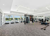 Thumbnail 25 of 41 - A spacious gym with a variety of equipment and a view of the outdoors through large windows.