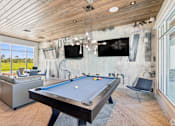 Thumbnail 41 of 41 - A pool table is in the middle of a room with a tv and a chair.