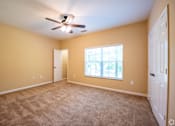 Thumbnail 14 of 26 - A room with a ceiling fan and carpeted floor.