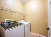 Thumbnail 13 of 26 - A white dryer and washer are in a small laundry room.