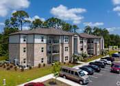 Thumbnail 1 of 8 - A parking lot in front of a building with a red car in the foreground. at Arbours at Kingsland, Georgia, 31548