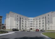Thumbnail 13 of 32 - A large white building with a parking lot in front at Arbours at Tumblin Creek ~ Active 55+ Adult Community, Florida