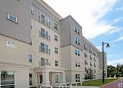 Thumbnail 17 of 32 - A modern apartment building with a parking lot in front at Arbours at Tumblin Creek ~ Active 55+ Adult Community, Gainesville 32608