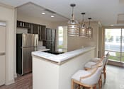 Thumbnail 21 of 32 - A kitchen with a refrigerator, bar stools, and pendant lights at Arbours at Tumblin Creek ~ Active 55+ Adult Community, 32608