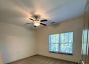 Thumbnail 8 of 17 - A room with a ceiling fan and carpeted floor.