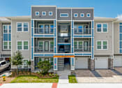 Thumbnail 1 of 41 - A modern apartment building with a grey and blue exterior and a red and white striped awning.