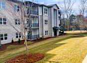 Thumbnail 1 of 17 - A tree in a mulched bed in front of a building at Arbours at Covington Apartments, Covington, GA, 30014