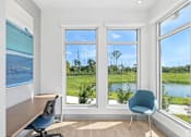 Thumbnail 20 of 41 - A room with a desk, chair and a view of a field and trees.