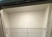 Thumbnail 11 of 17 - A walk-in closet with a carpeted floor and white walls.