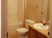 Thumbnail 11 of 18 - A white toilet sits next to a sink in a bathroom at Arbours at Ensley Apartments, Florida