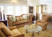 Thumbnail 1 of 18 - A living room with a tan couch, a glass coffee table, and a chandelier at Arbours at Ensley Apartments, Pensacola, 32514