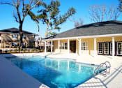 Thumbnail 3 of 18 - A swimming pool in front of a house with a tree at Arbours at Ensley Apartments, Pensacola