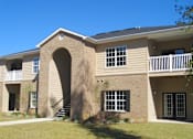 Thumbnail 7 of 18 - A beige building with a balcony and a staircase at Arbours at Ensley Apartments, Pensacola, FL