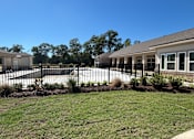 Thumbnail 2 of 5 - A black fence surrounds a building with a white roof at Arbours at Lake Charles, Lake Charles, LA