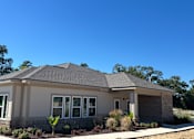 Thumbnail 5 of 5 - A house with a grey roof and white walls with a small garden in front at Arbours at Lake Charles, Lake Charles