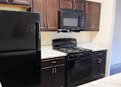 Thumbnail 4 of 17 - Kitchen with Black Appliances at Arbours at Covington Apartments, Georgia