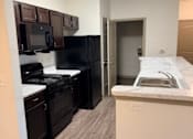 Thumbnail 13 of 17 - A kitchen with black appliances and a white counter.