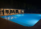 Thumbnail 2 of 17 - A swimming pool at night with lights on.