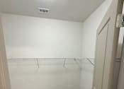 Thumbnail 7 of 17 - A white closet with a carpeted floor and a white door.