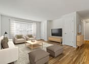 Thumbnail 7 of 27 - A living room with a white couch, a brown ottoman, a wooden coffee table, and a flat-screen TV. at Chatham Hill, New Jersey, 07928