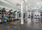 Thumbnail 6 of 13 - A gym with a variety of equipment including weight plates, weightlifting equipment, and a bench press at The Addison, Baton Rouge, Louisiana