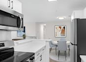 Thumbnail 14 of 20 - A modern kitchen with a black stove top oven and a black refrigerator.