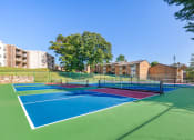 Thumbnail 14 of 51 - tennis courts with apartments in the background at Copper and Quarry Village, Pikesville