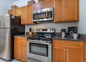 Thumbnail 20 of 46 - a kitchen with stainless steel appliances and wooden cabinets at Pier Village Apartments, New Jersey
