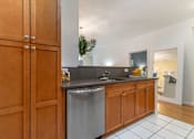 Thumbnail 21 of 46 - a kitchen with a stainless steel dishwasher and wooden cabinets at Pier Village Apartments, Long Branch, New Jersey