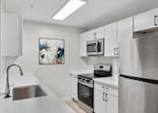 Thumbnail 2 of 26 - A modern kitchen with stainless steel appliances and white cabinets at Grand at Pearl Apartments, Pearl, MS