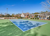 Thumbnail 16 of 18 - A tennis court with a net and a building in the background at Greenbrier Estates, Slidell, 70460