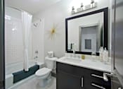 Thumbnail 12 of 13 - a bathroom with a white toilet next to a bathtub with a shower curtain at The Addison,Louisiana