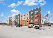 Thumbnail 1 of 30 - A row of apartment buildings with cars parked in front.