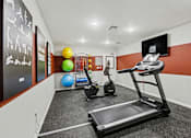 Thumbnail 8 of 31 - A gym with a treadmill, exercise ball, and other equipment.