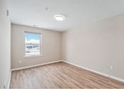 Thumbnail 6 of 30 - Empty room with wooden floor and white walls.