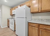 Thumbnail 3 of 31 - A white refrigerator in a kitchen with wooden cabinets.