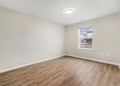 Thumbnail 10 of 31 - A room with wooden flooring and a window showing a tree outside.