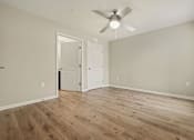 Thumbnail 14 of 22 - A room with a ceiling fan and wooden flooring.