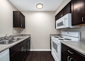 Thumbnail 18 of 40 - a kitchen with white appliances and dark cabinets