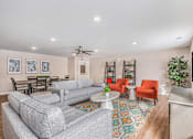 Thumbnail 18 of 30 - A living room with a grey couch, a red chair, a white coffee table, and a ceiling fan.