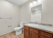 Thumbnail 11 of 31 - A bathroom with a toilet, sink, and mirror.