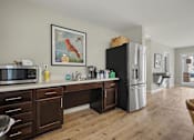 Thumbnail 11 of 22 - A kitchen with a black fridge, wooden cabinets, and a painting of a rooster on the wall.