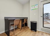 Thumbnail 10 of 22 - A room with a desk and chairs and a trash can.