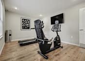 Thumbnail 6 of 22 - A home gym with a treadmill, a stationary bike, and a weight machine.