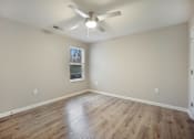 Thumbnail 28 of 43 - A room with a ceiling fan and wooden flooring.
